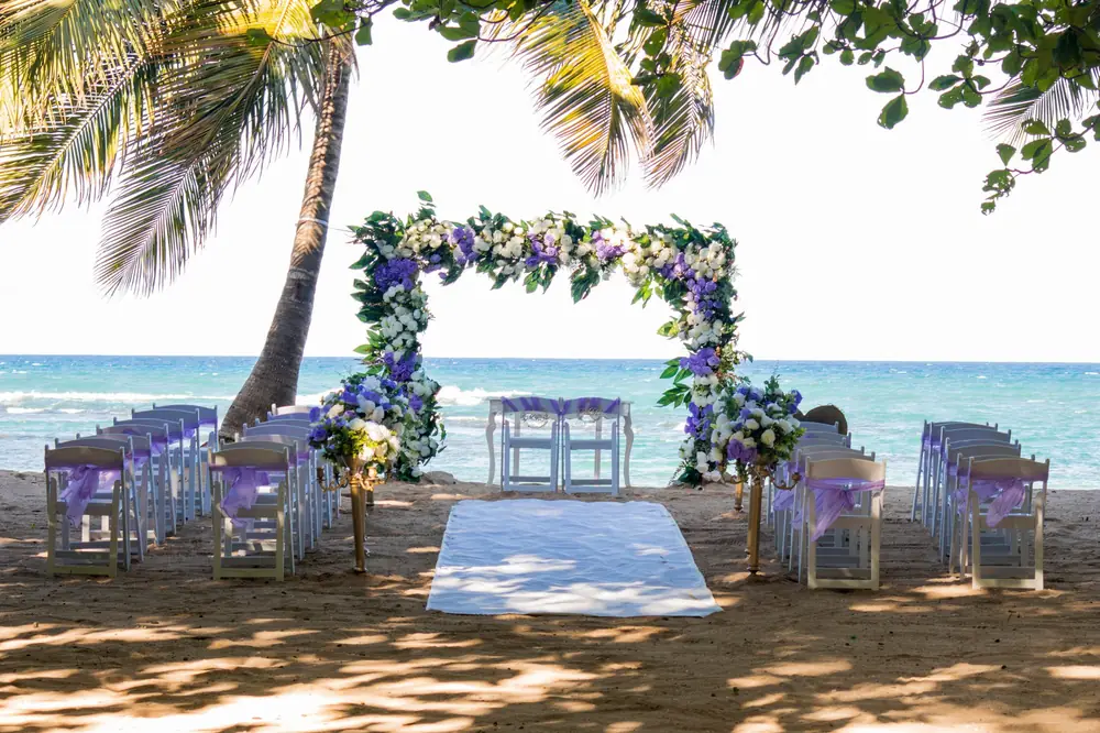 Beach wedding setup with a floral arch under palm trees in Puerto Plata